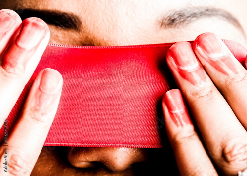 A person's eyes are covered with a red ribbon