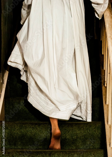 A person in a white dress descends a staircase.