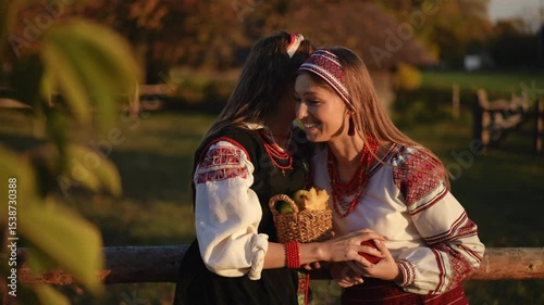 Two women dressed in traditional cultural attire share a joyful and candid moment in a stunning natural setting