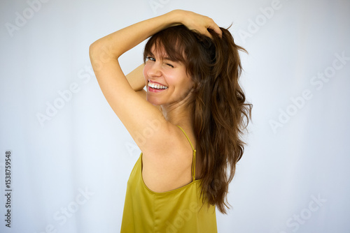 Beautiful happy playful brunette with the big smile holding her beautiful long thick hair on the white background
