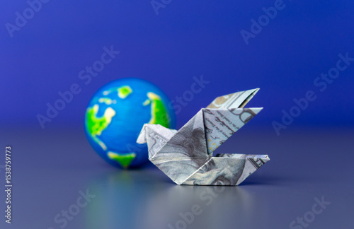An origami bird folded from a US dollar bill and a globe. Global finance, international trade, and the worldwide movement of money.