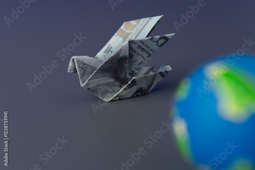 An origami bird folded from a US dollar bill and a globe. Global finance, international trade, and the worldwide movement of money.