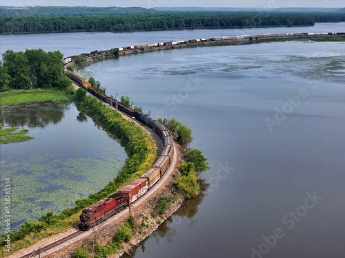 Railroad locomotive pulling a freight train of mixed car types along the Mississippi river