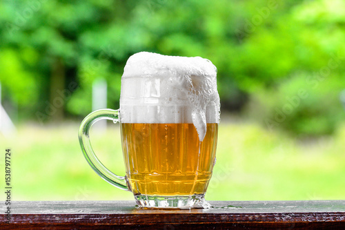 Fototapet Beer garden, foam pouring from the brewery in a mug, the sun is shining