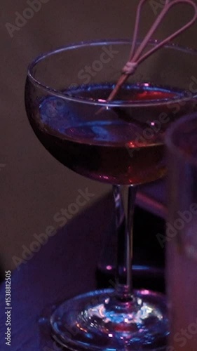 the bartender behind the bar makes a black unusual alcoholic cocktail, a very beautiful drink in a nightclub, expensive alcohol in a glass of a luxury restaurant