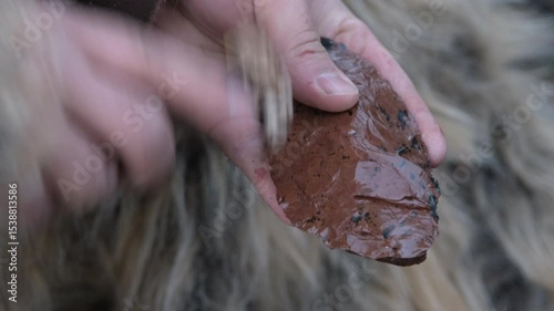 A craftsman uses an antler tool for pressure flaking to sharpen a prehistoric flint tool. A close-up on ancient technology and survival skills.