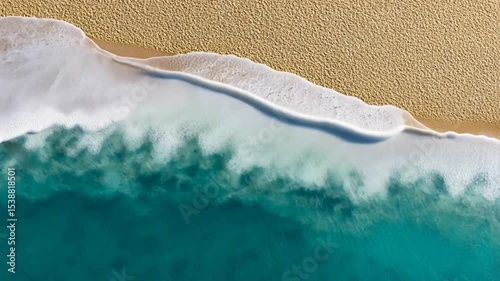 Aerial view of turquoise ocean waves gently lapping against a sandy beach, evoking tranquility and natural beauty.