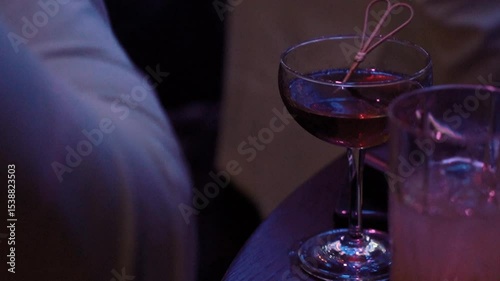 the bartender behind the bar makes a black unusual alcoholic cocktail, a very beautiful drink in a nightclub, expensive alcohol in a glass of a luxury restaurant