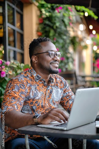 Smiling Man Working on Laptop at Outdoor Café