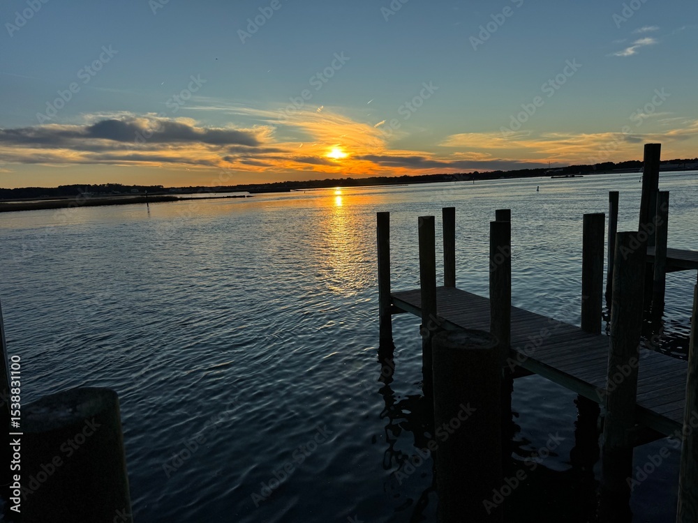 Obraz premium Wooden dock at golden sunset over quiet bay