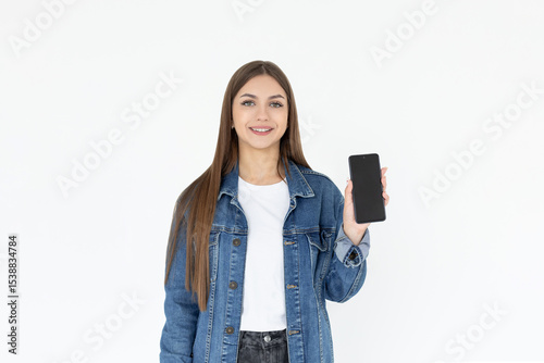 Close up portrait of a smiling woman showing blank screen mobile phone while standing isolated over white background