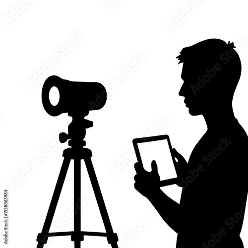 Silhouette of fashion photographer using tablet to control camera settings  