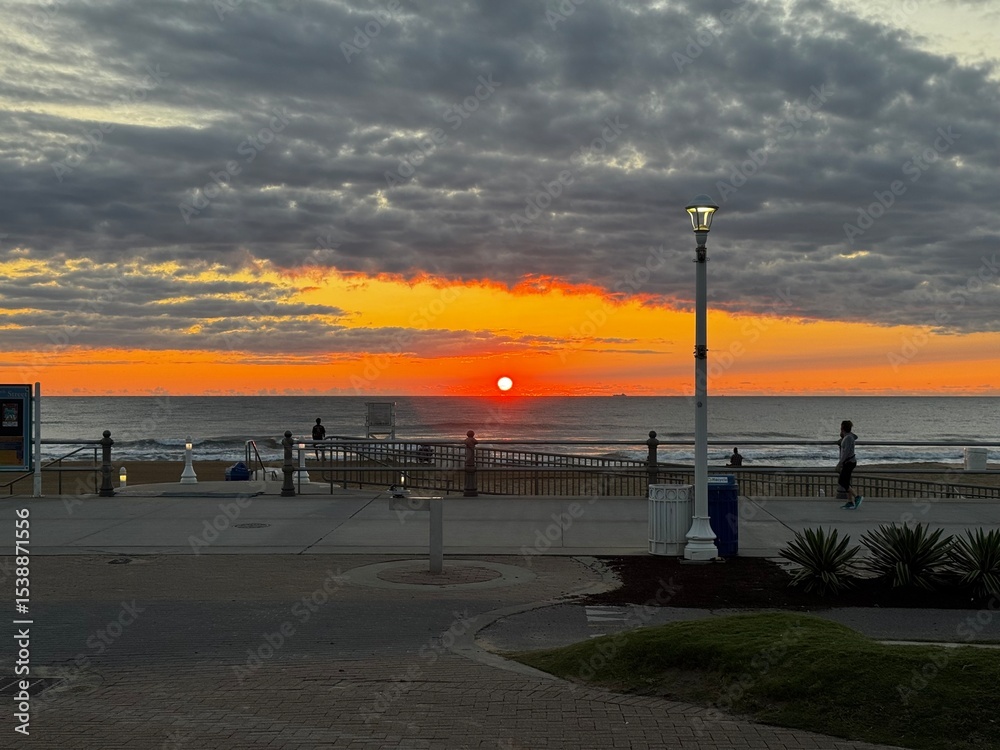 Foto Vibrant sunrise over Virginia Beach oceanfront with glowing clouds and quiet boa