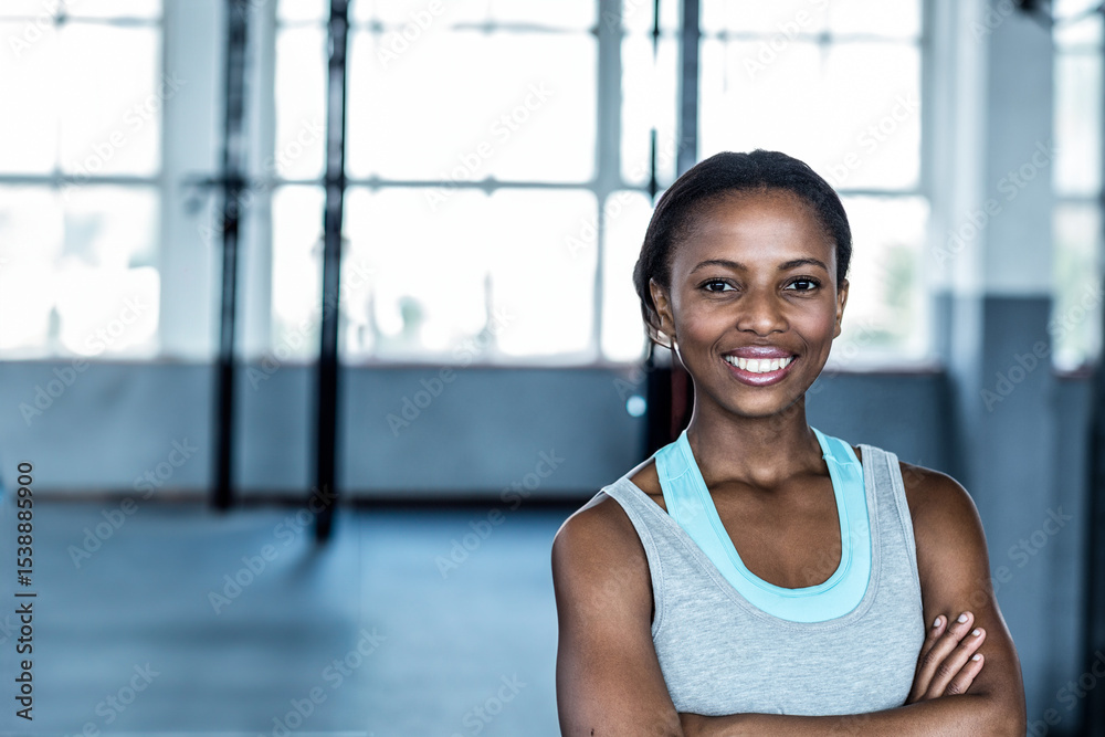 African American woman standing with arms folded in gym studio by metal rigs, windows, copy space African American woman standing with arms folded in gym studio by metal rigs, windows, copy space