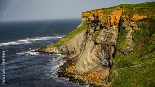 Breathtaking view of dramatic cliffs meeting the North Sea, showcasing the rugged beauty of the North York Moors National Park coastline