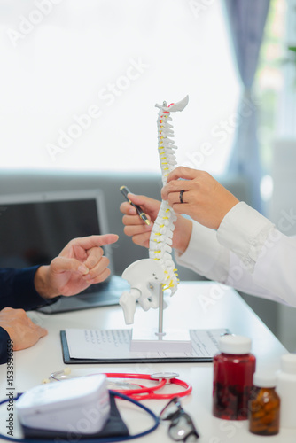 An orthopedic doctor shows a spinal model to a patient in a human spinal hospital. Diseases and disorders of the spinal cord, back pain, lumbar pain, orthopedic surgery, chiropractic, office syndrome