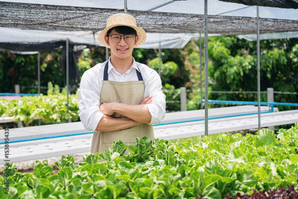 Obraz premium A man in a white shirt and apron stands in front of a row of plants