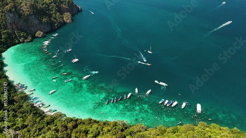 Turquoise water and white sand beach at Maya Bay, with boats and tourists enjoying the beautiful landscape, Phi phi island, Thailand.