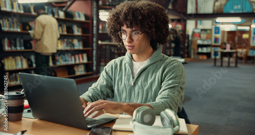 Student, laptop and typing in library with man for studying, assignment or thesis on college campus. Computer, writing and male person with education, preparation for exam or research for paper