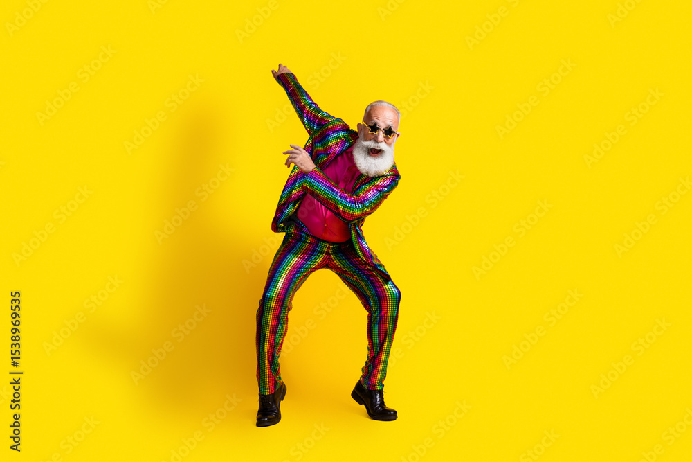 Naklejka premium Charismatic senior man dancing in vibrant suit against a bright yellow backdrop, radiating joy and style