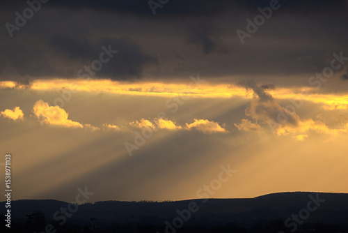 Dramatic golden sun rays breaking through dark clouds.