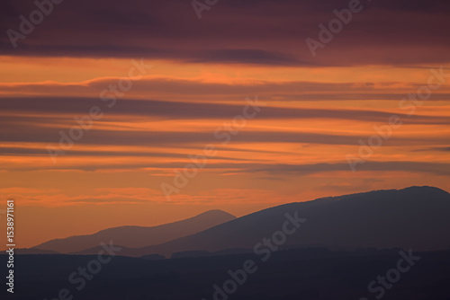 Vibrant orange and purple sunset stripes above mountains.