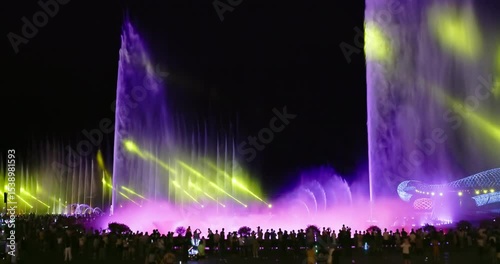 Magnificent musical water fountain show dazzling with colorful lights and laser projections at night in front of a large crowd.