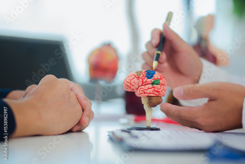 Female doctor gives advice and explanation to patient with dementia and stroke in examination room using human brain anatomy model and blood pressure measurement. Healthcare and medical concept.	