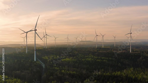 Wind turbines park inside a forest, drone aerial video at sunrise
