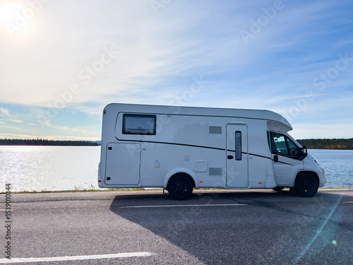 White camper van parked near lake enjoying scenic view on a sunny day, perfect for road trip and vacation