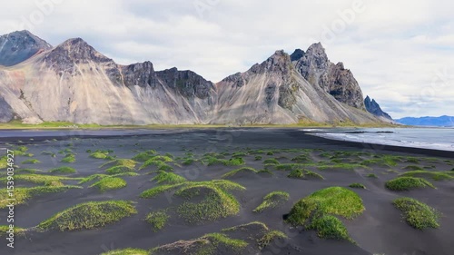 Majestic Coastal Landscape featuring Mountains and Expansive, Lush Green Dyunes Nearby. Stokksnes. Iceland
