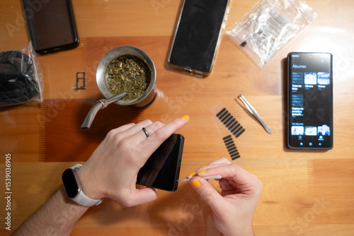 Primer plano manos reparando celular enfoque selectivo colocando filtro en parlante del móvil, mate en la mesa