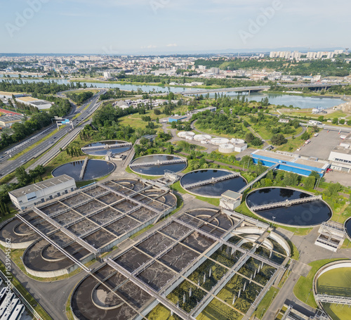 Eco-friendly aerial view of wastewater treatment plant near Lyon, France, with urban skyline – sustainable water management and environmental protection concept