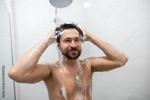 Brunette man rinsing hair in white bathroom
