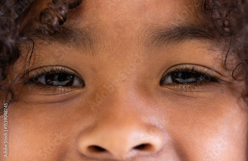 Close-up of boy's joyful eyes and curly hair, expressing happiness and curiosity, at school