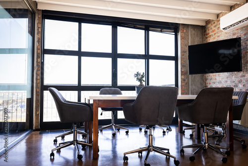 Modern office conference room with empty chairs around large wooden table, copy space
