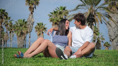 Joyful couple sharing laughter and smiles while sitting together on a beautiful sunny day in the park. High quality 4k footage