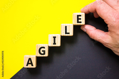 Agile symbol. Concept word Agile on beautiful wooden blocks. Beautiful yellow and black background. Businessman hand. Business agile concept. Copy space.