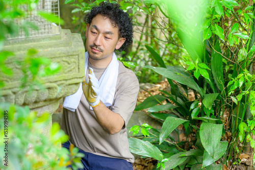 石灯籠を正面から見つめながら両手でゆっくり触れて状態を確かめる男性の落ち着いた作業風景 photo