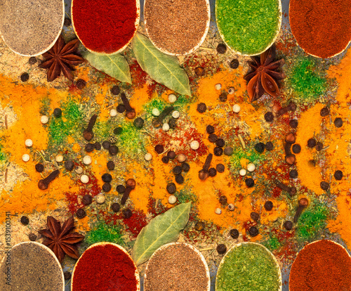Fototapeta Naklejka Na Ścianę i Meble -  Background of multi-colored spices in spoons: turmeric, paprika, black and white pepper on rough burlap.