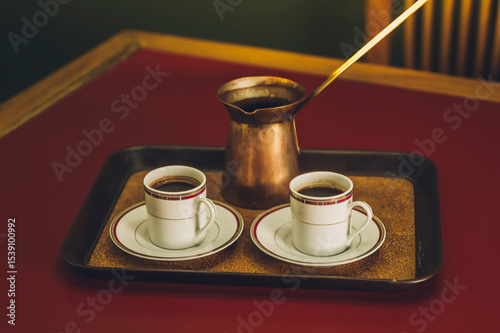 Traditional Arabic coffee in its copper jug, with two cups to serve it.