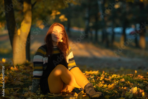 Portrait of a young beautiful red-haired girl in an autumn city park.