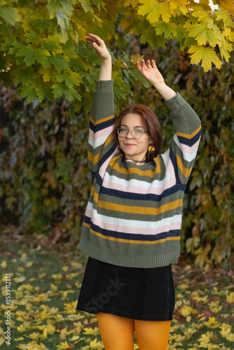 Portrait of a young beautiful red-haired girl in an autumn city park.