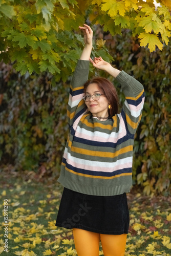 Portrait of a young beautiful red-haired girl in an autumn city park.