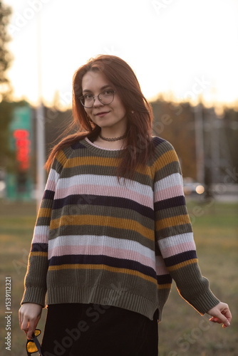 Portrait of a young beautiful red-haired girl in an autumn city park.