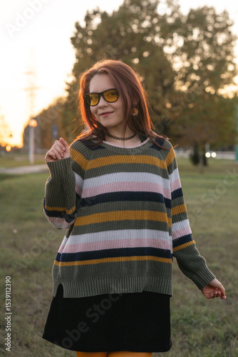 Portrait of a young beautiful red-haired girl in an autumn city park.