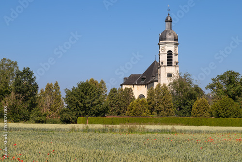 The Saint John the Evangelist Church of Park Abbey seen from a grain field with poppies in Heverlee, Leuven.