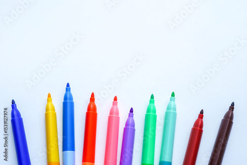 A row of colorful felt-tip markers is arranged in a semi-circle on a white background