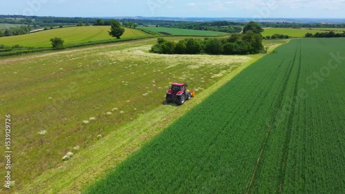 Aerial shot of tractor working in an English field in Summer