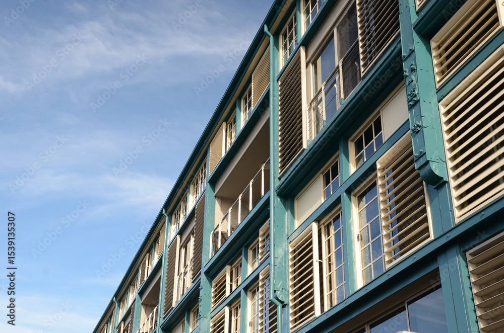 Modern building exterior with glass and teal accents under clear blue sky Modern building exterior with glass and teal accents under clear blue sky